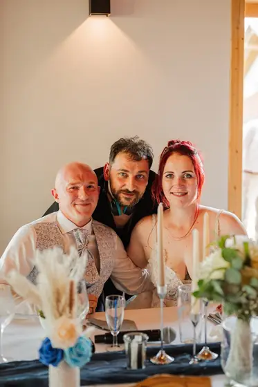 Brautpaar am Hochzeitstisch, DJ Stefan lächelt zwischen den beiden
