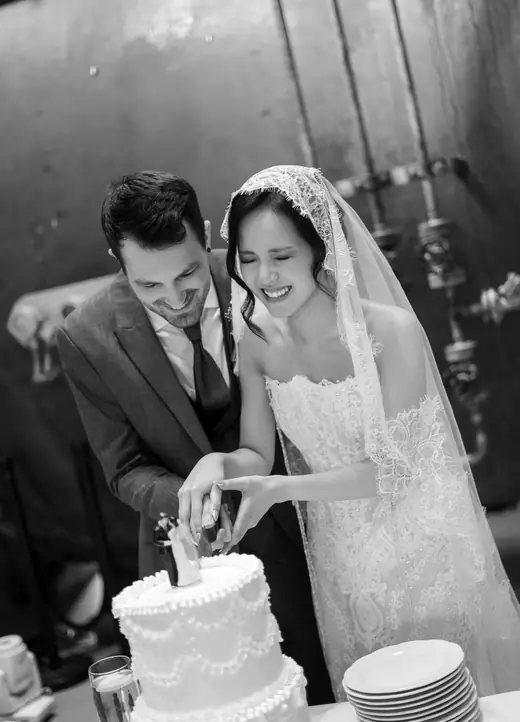 Brautpaar schneidet lachend die Hochzeitstorte an