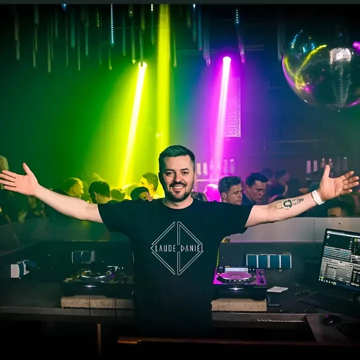 DJ Claudius mit ausgebreiteten Armen vor einer Lichtshow