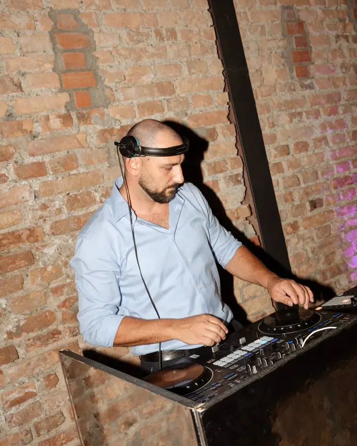 DJ Stefan Rocheanu legt mit Kopfhörern vor einer Backsteinwand auf
